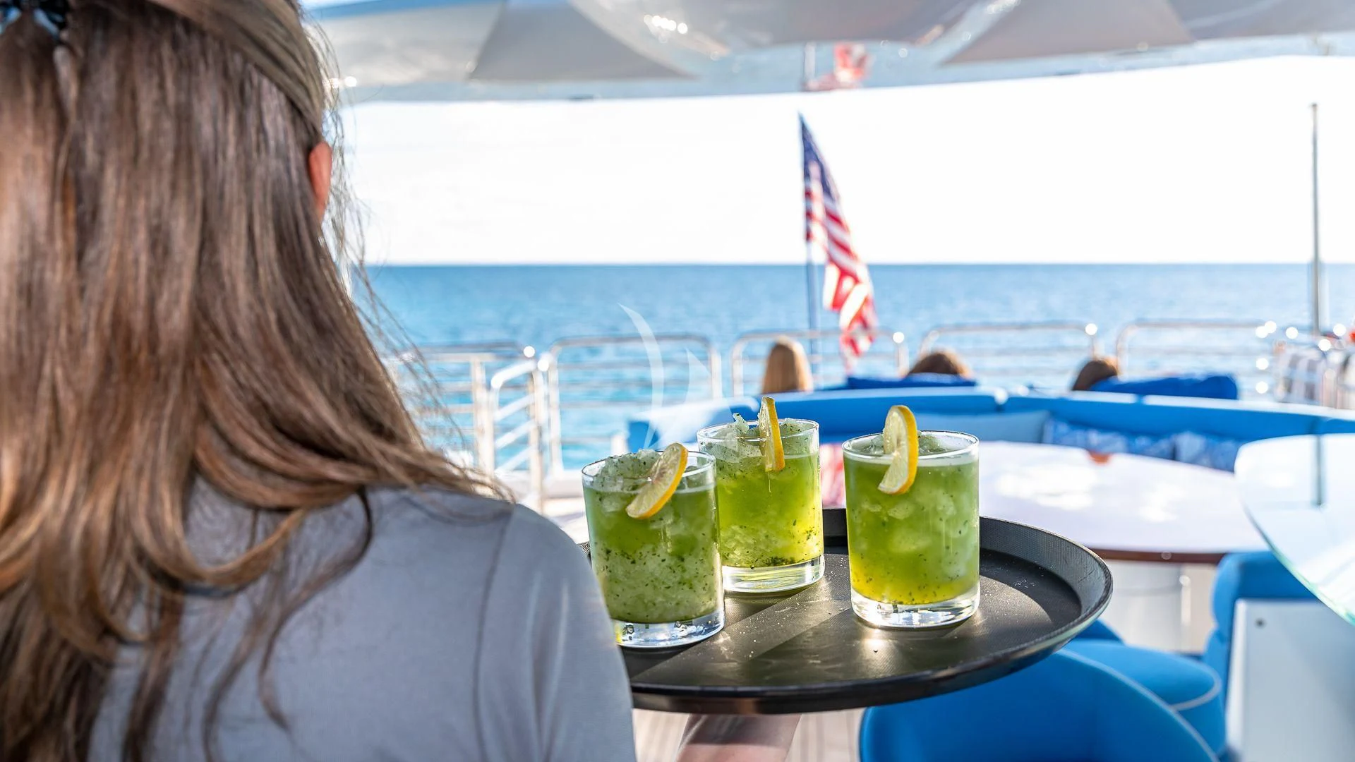 a woman sitting at a table with drinks and fruit on it aboard KEFI Yacht for Charter