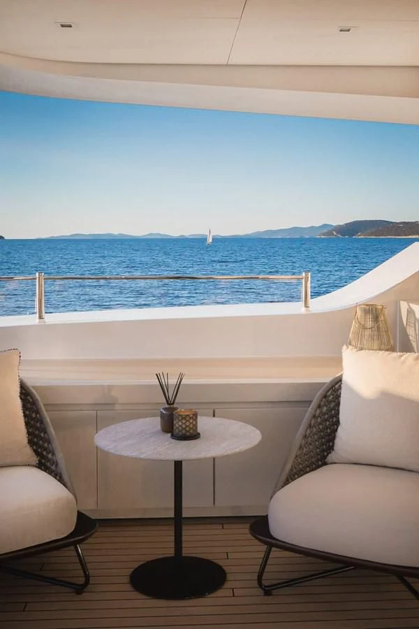 a table and chairs on a balcony overlooking the ocean aboard LAMMOUCHE Yacht for Sale
