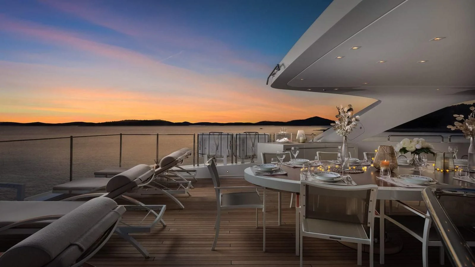 a large white table with chairs on it and a sunset in the background aboard LAMMOUCHE Yacht for Sale