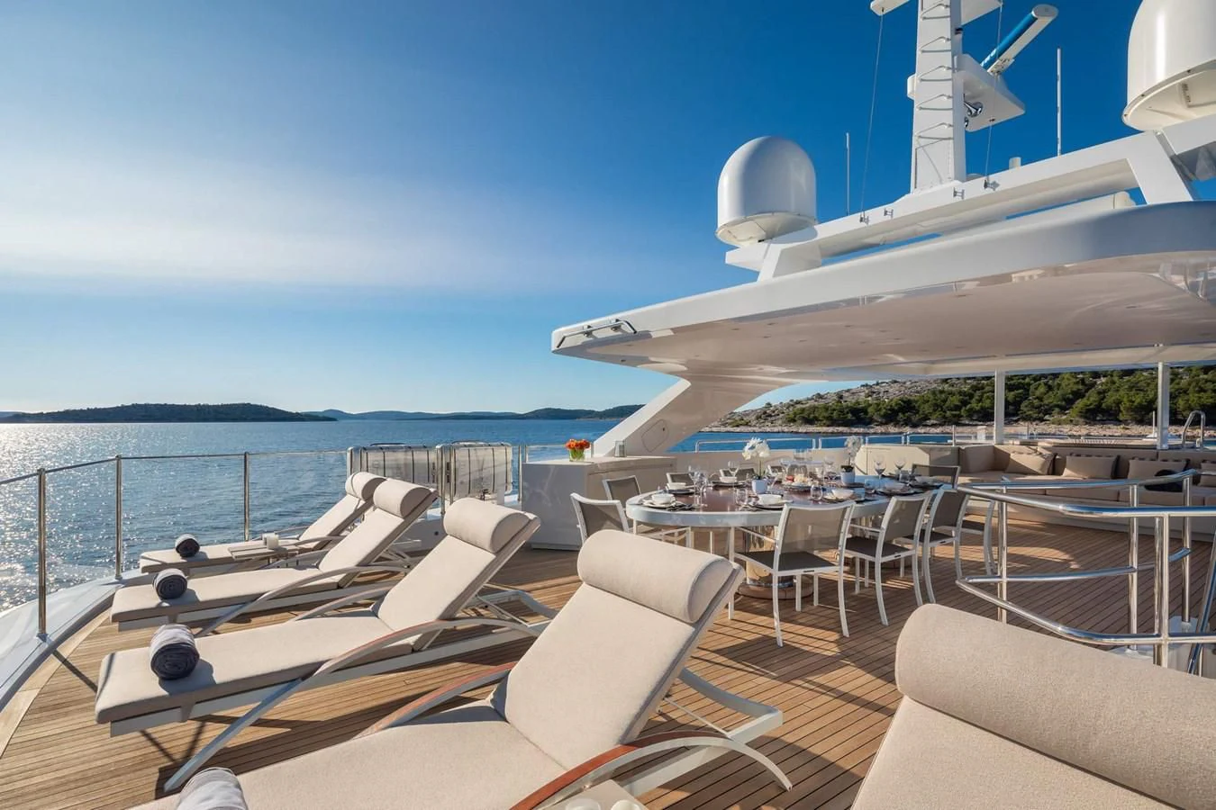 a deck with chairs and tables on it by a body of water aboard LAMMOUCHE Yacht for Sale
