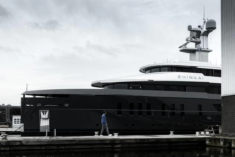 a person walking on a dock next to a large boat aboard SHINKAI Yacht for Sale