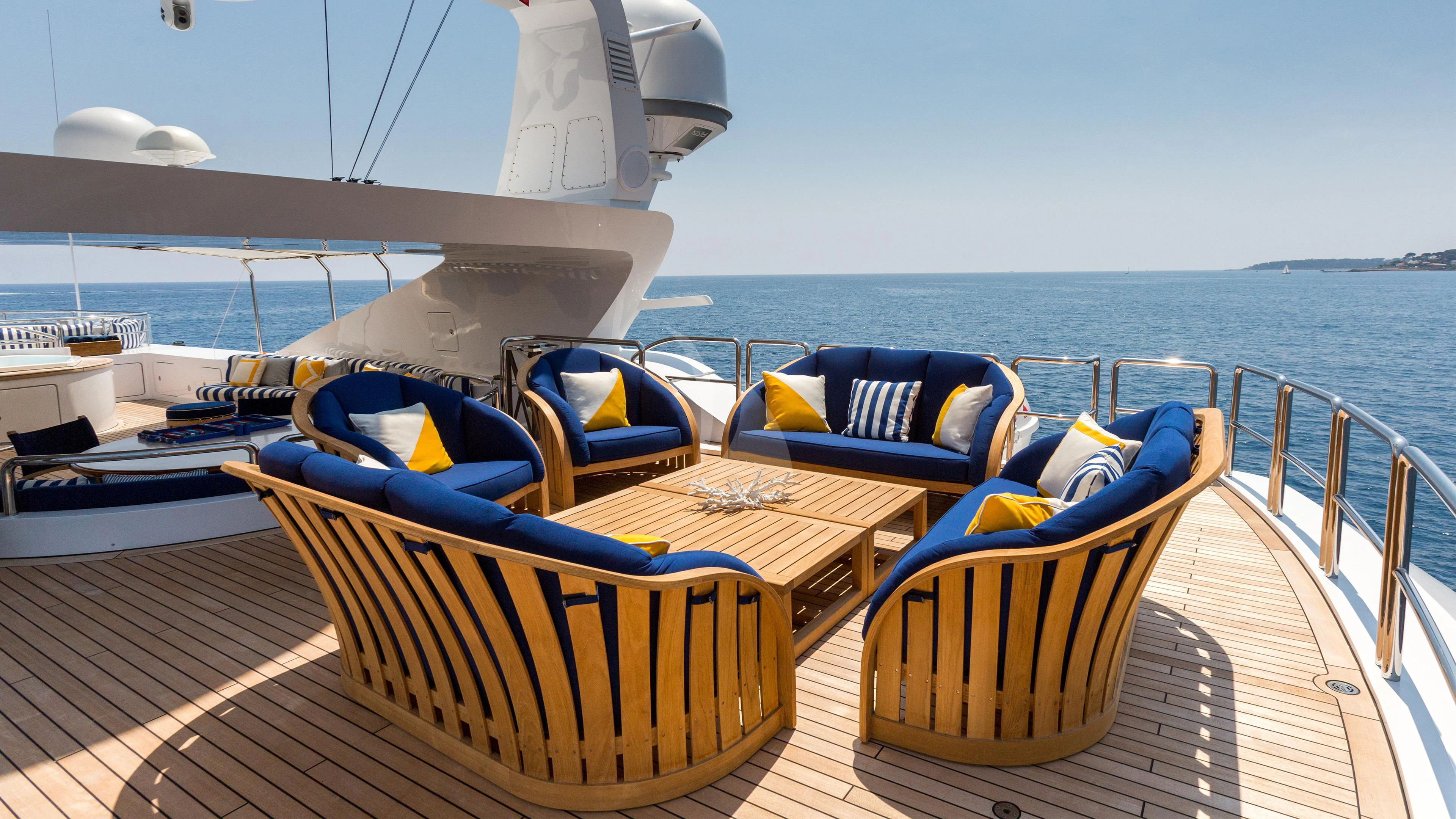a deck with chairs and a table on it aboard AIR Yacht for Sale