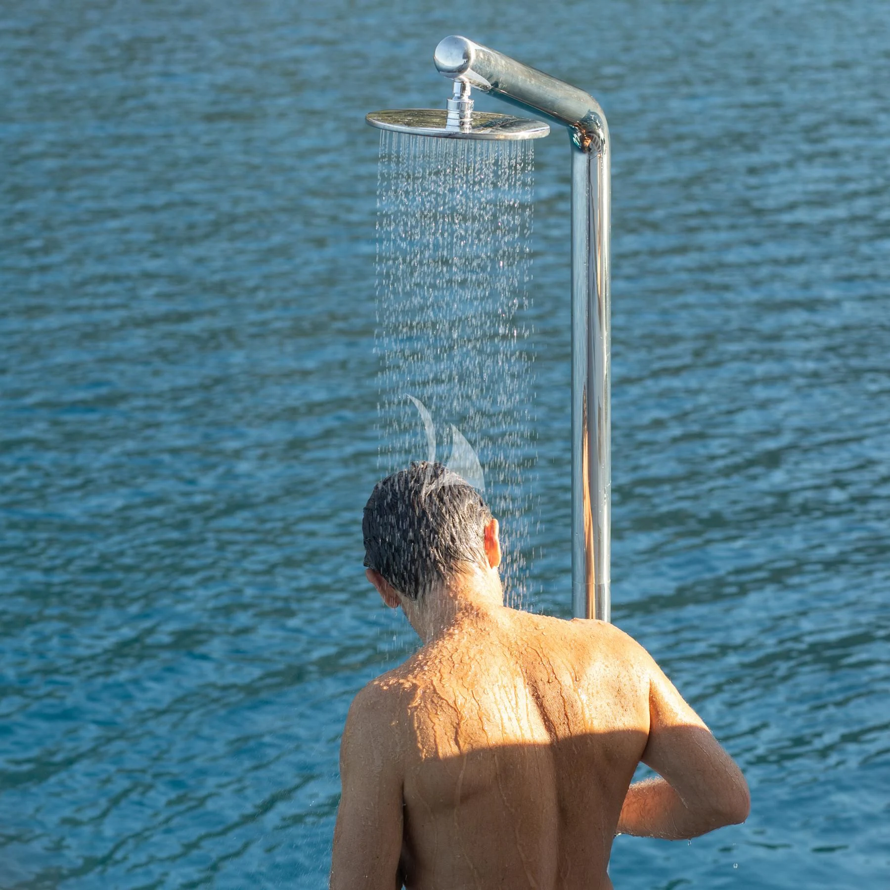 a man with a shower head in the water aboard EDEN Yacht for Sale