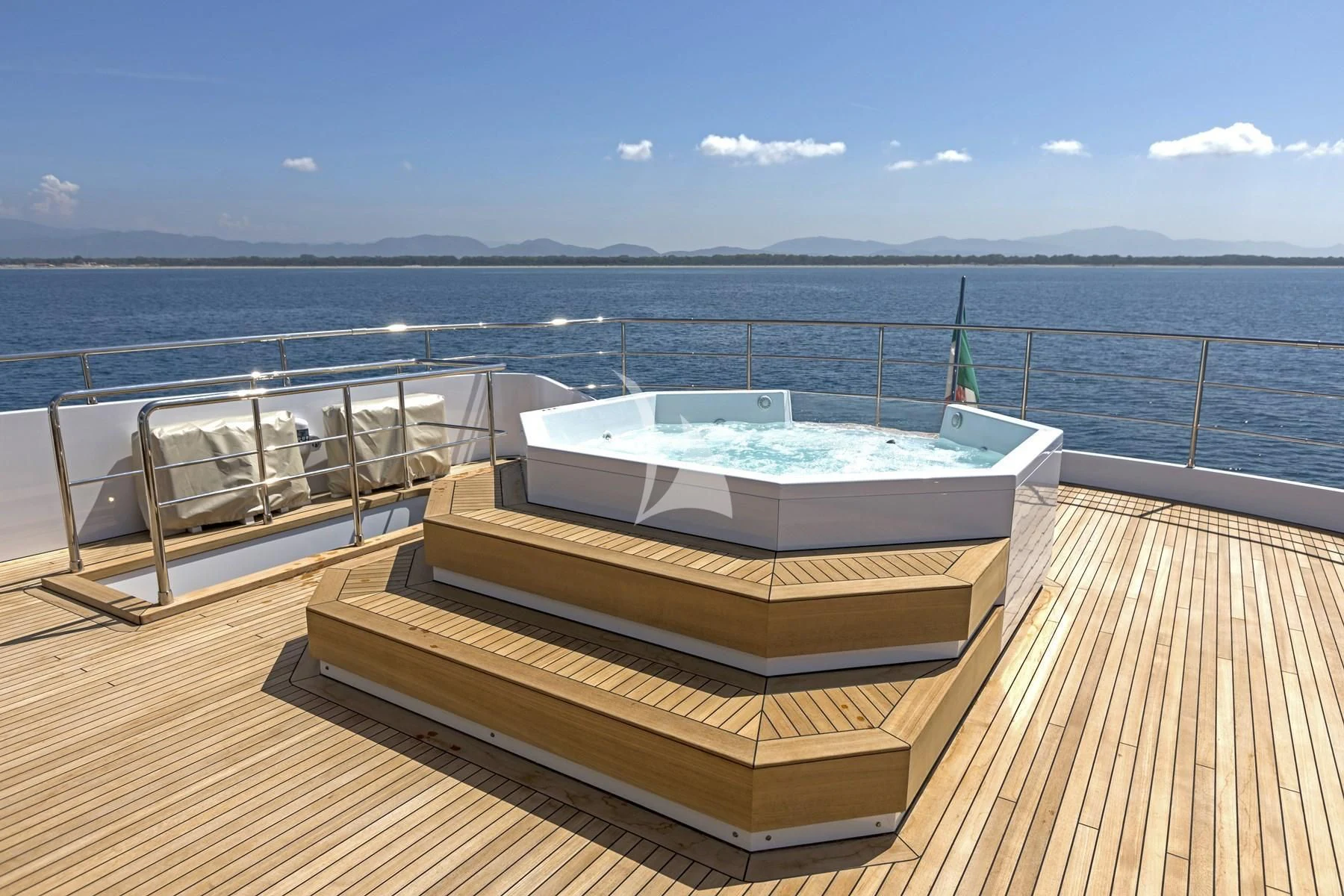 a deck with a view of the ocean and mountains in the background aboard EDEN Yacht for Sale