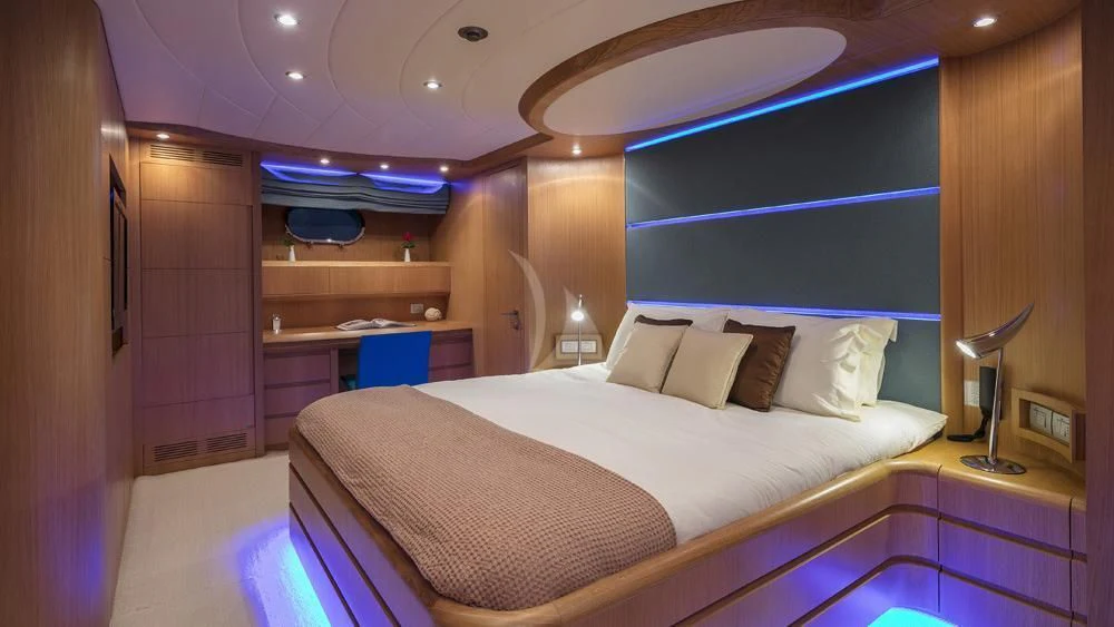 a bed with a white sheet and pillows in a room with a wood door and a mirror aboard ANASA Yacht for Sale