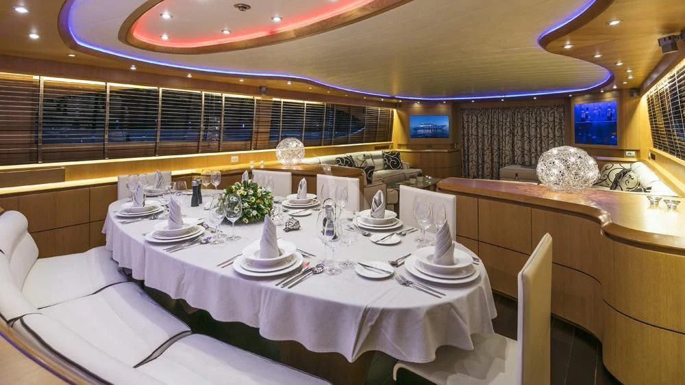 a large white table with plates and chairs aboard ANASA Yacht for Sale