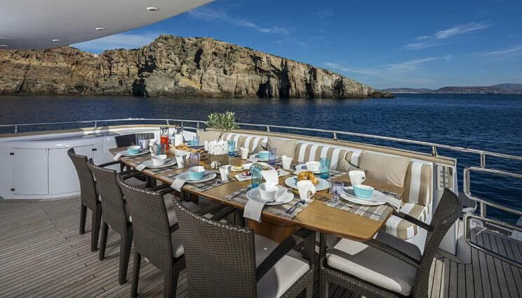 a table set for a meal on a deck overlooking the ocean aboard ANASA Yacht for Sale