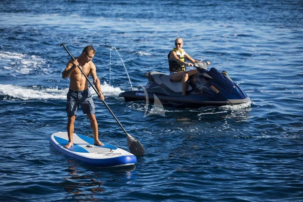 a man and a woman on a paddle board in the water aboard ANASA Yacht for Sale