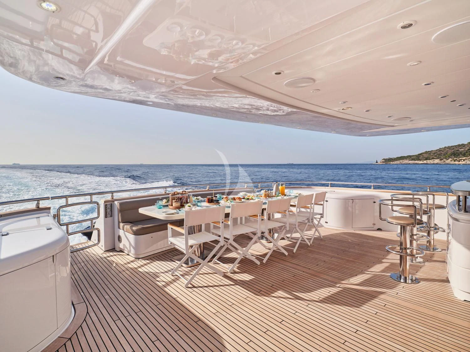 a room with a table and chairs on a deck with a body of water in the background aboard ANASA Yacht for Sale