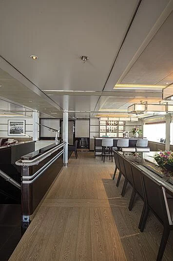 a long wooden hallway with tables and chairs aboard M5 Yacht for Sale