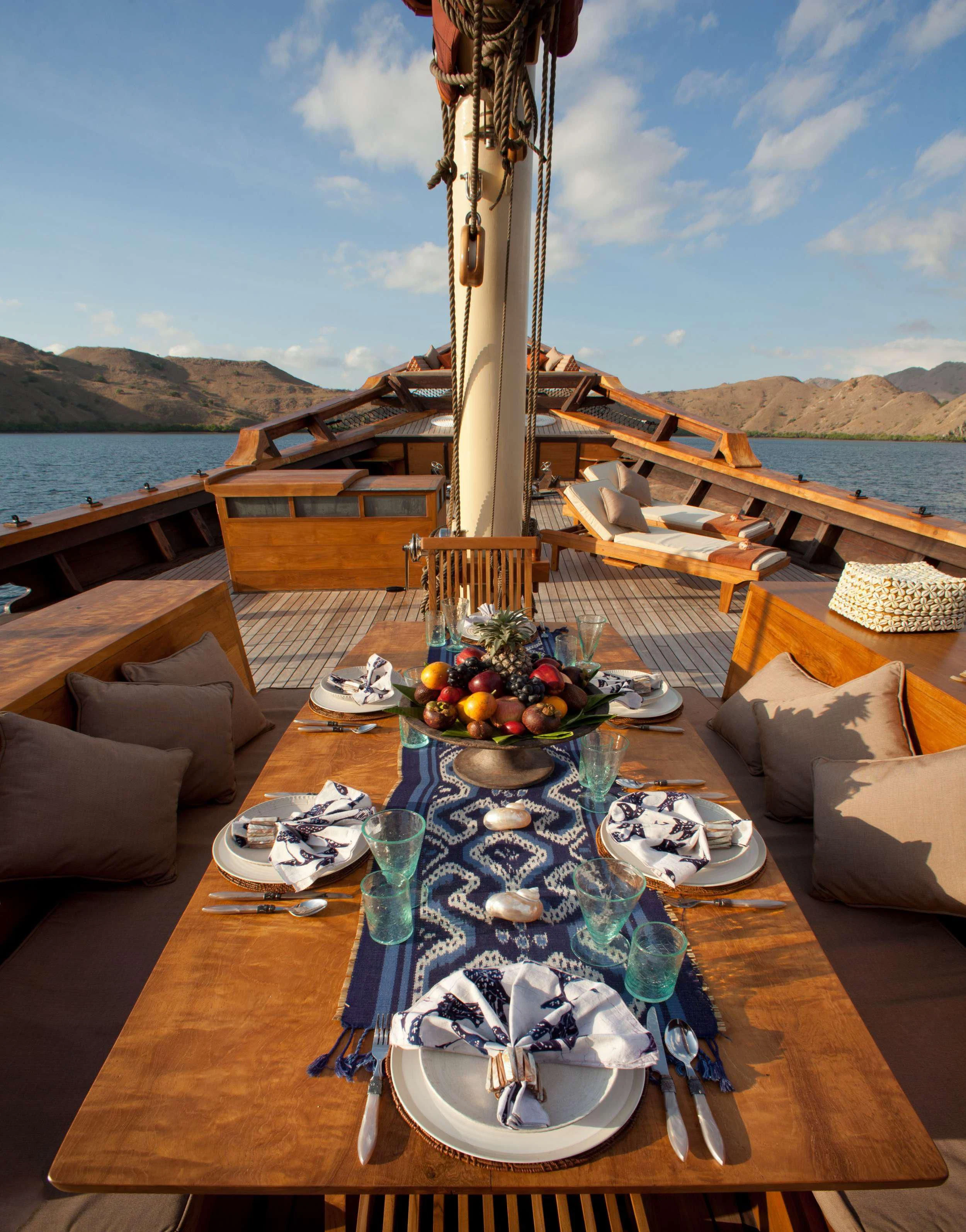a table with plates and food on it aboard SI DATU BUA Yacht for Sale