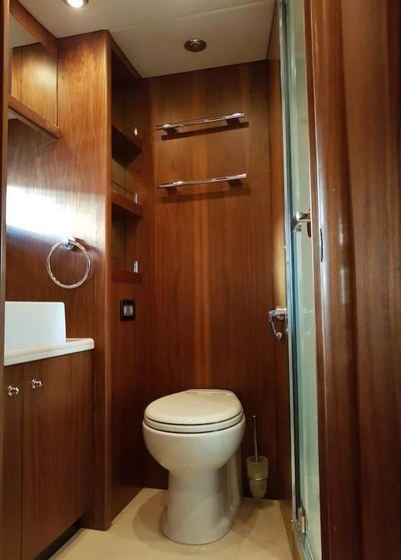 a bathroom with a toilet and wooden cabinets aboard LAURA S Yacht for Sale