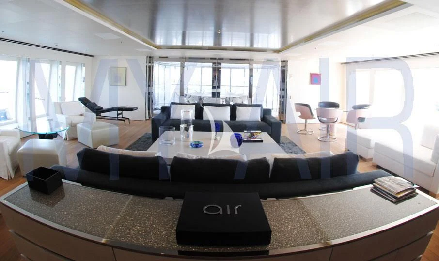 a large living room with a large black leather couch and a large window aboard AIR Yacht for Sale