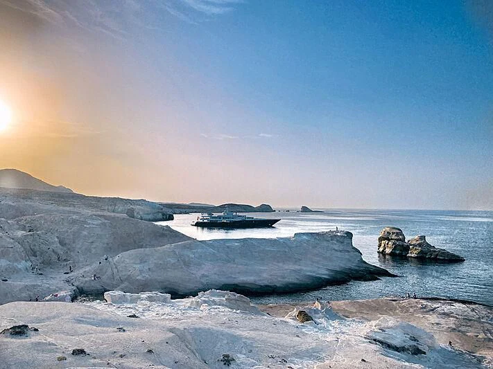a snowy landscape with a boat on the water and mountains in the background aboard AIR Yacht for Sale