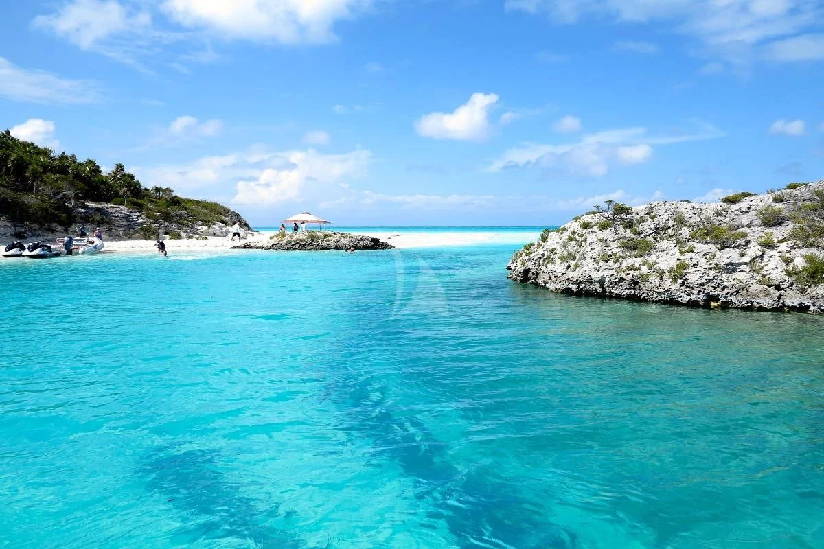a body of water with rocks and a beach in the background aboard LE MONTRACHET Yacht for Sale