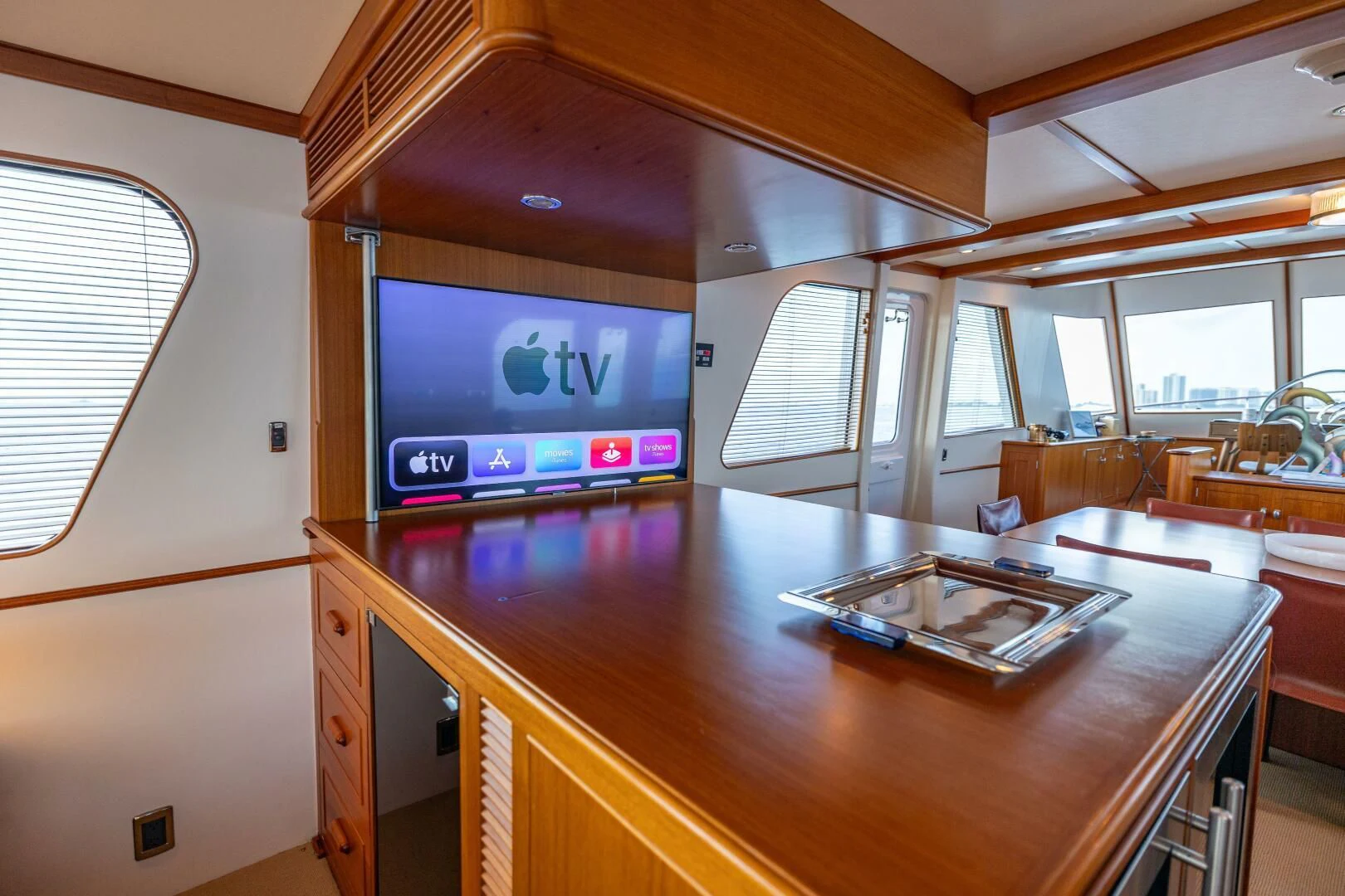a large flat screen television on a wooden table in a room with chairs and a window aboard SEA BOLD Yacht for Sale