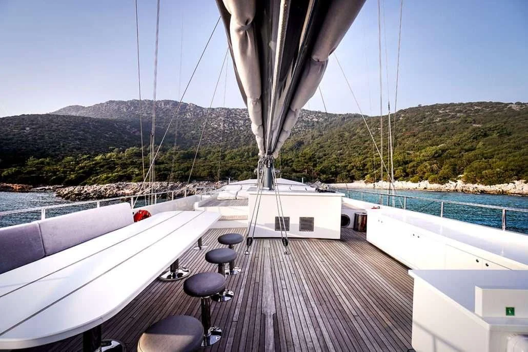 a deck with a deck and a view of mountains and water aboard VIRTUOSO Yacht for Sale