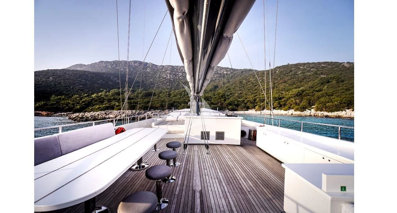 a deck with a deck and a view of a mountain range aboard VIRTUOSO Yacht for Sale
