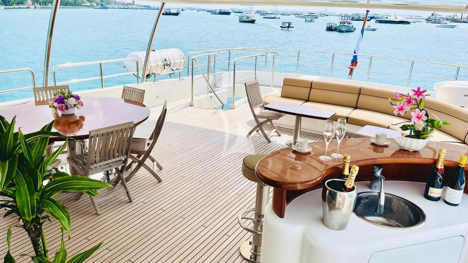 a table with wine bottles and chairs on it by a beach aboard GALAKTIKA SKAY Yacht for Sale