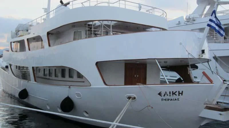 a large white boat with a flag on it aboard ELIKI Yacht for Sale