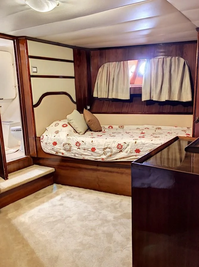 a bed with a white sheet and a wooden headboard aboard ELIKI Yacht for Sale