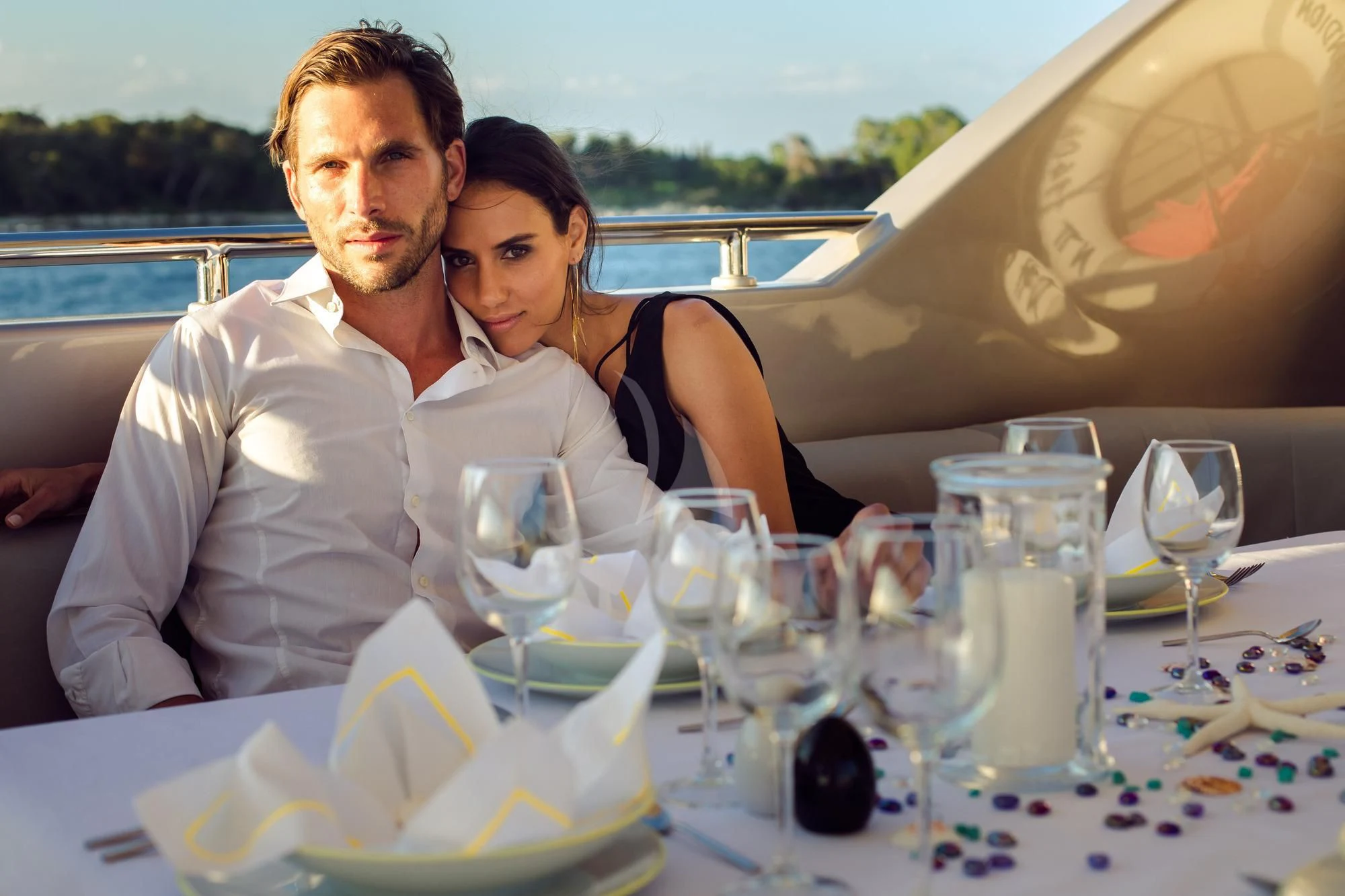 Benoit Gonzalez et al. kissing on a table with glasses of wine aboard PANDION Yacht for Charter