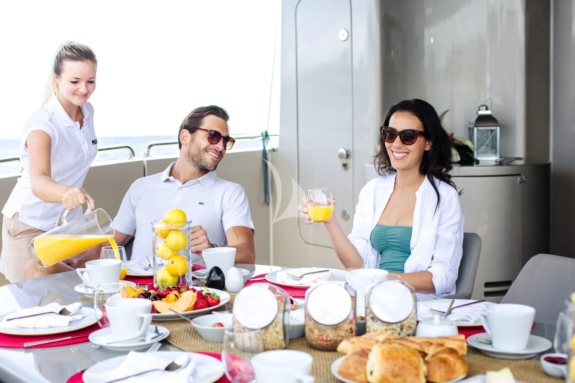 a group of people sitting around a table with food and drinks aboard PANDION Yacht for Charter