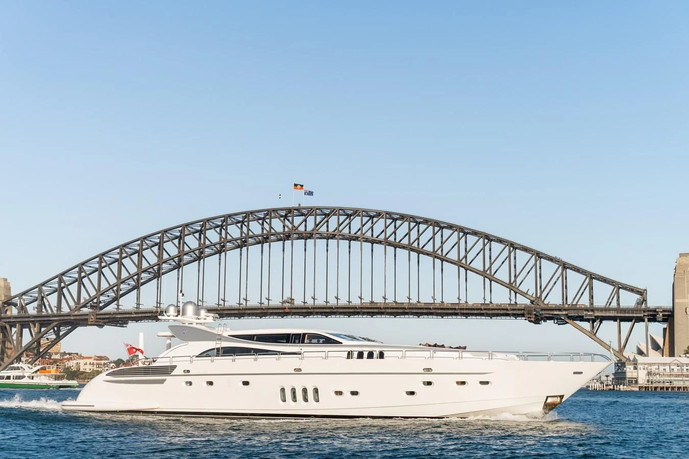 a large white boat in the water with Sydney Harbour Bridge in the background aboard YOLO Yacht for Sale
