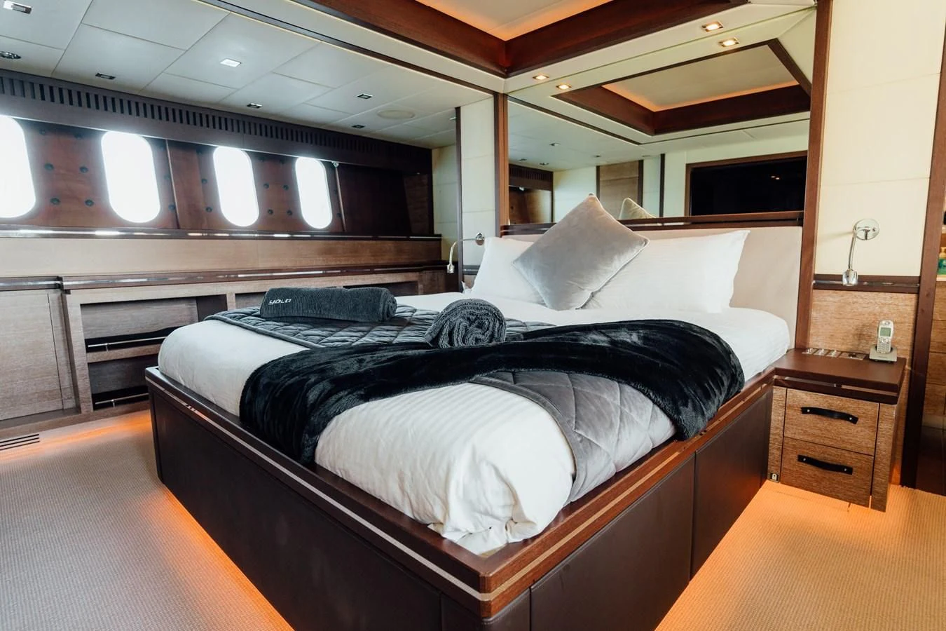 a bed with a black comforter aboard YOLO Yacht for Sale