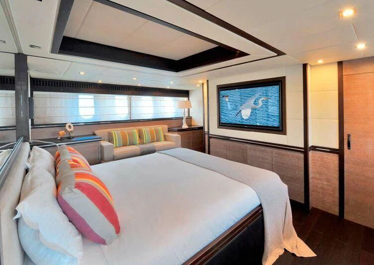 a room with a bed and a television on the wall aboard YOLO Yacht for Sale