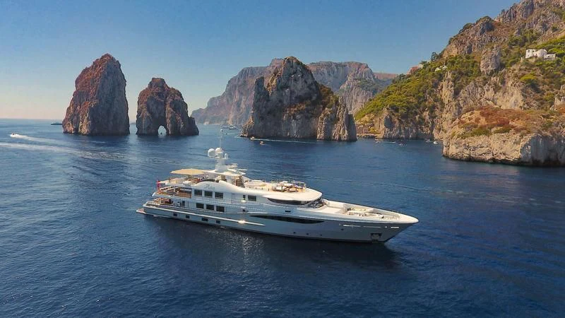 a boat on the water with Ha Long Bay in the background aboard ASTRA Yacht for Sale