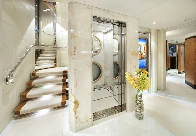 a large white room with a vase of flowers and a staircase aboard SYCARA V Yacht for Sale