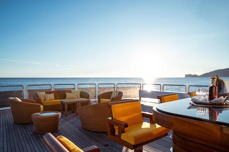 a table and chairs on a deck overlooking a body of water aboard BOADICEA Yacht for Sale