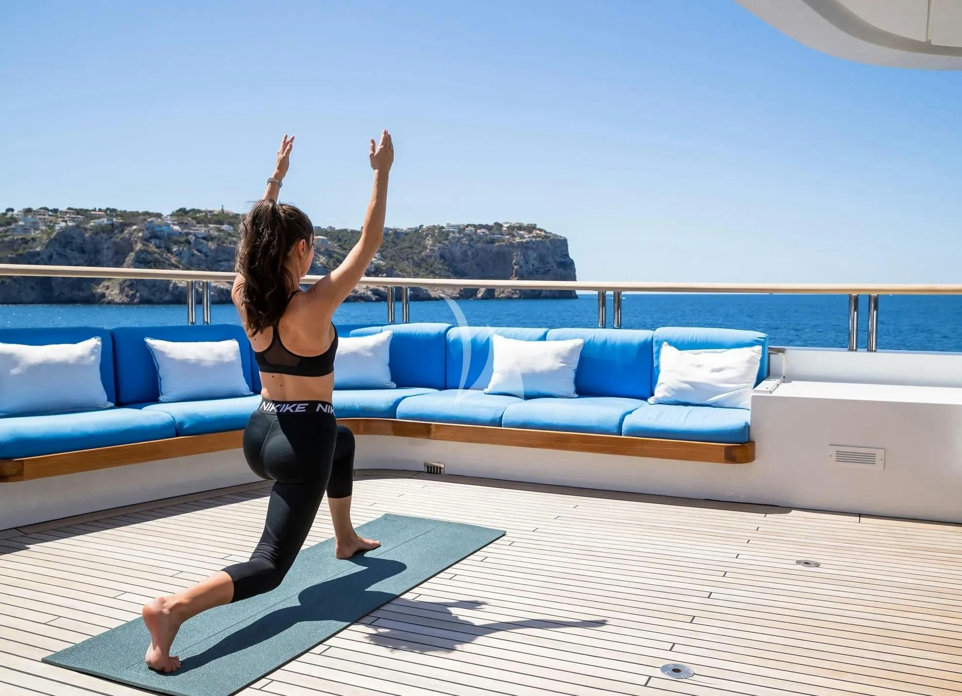 a woman in a bikini jumping in the air by a pool aboard BOADICEA Yacht for Sale