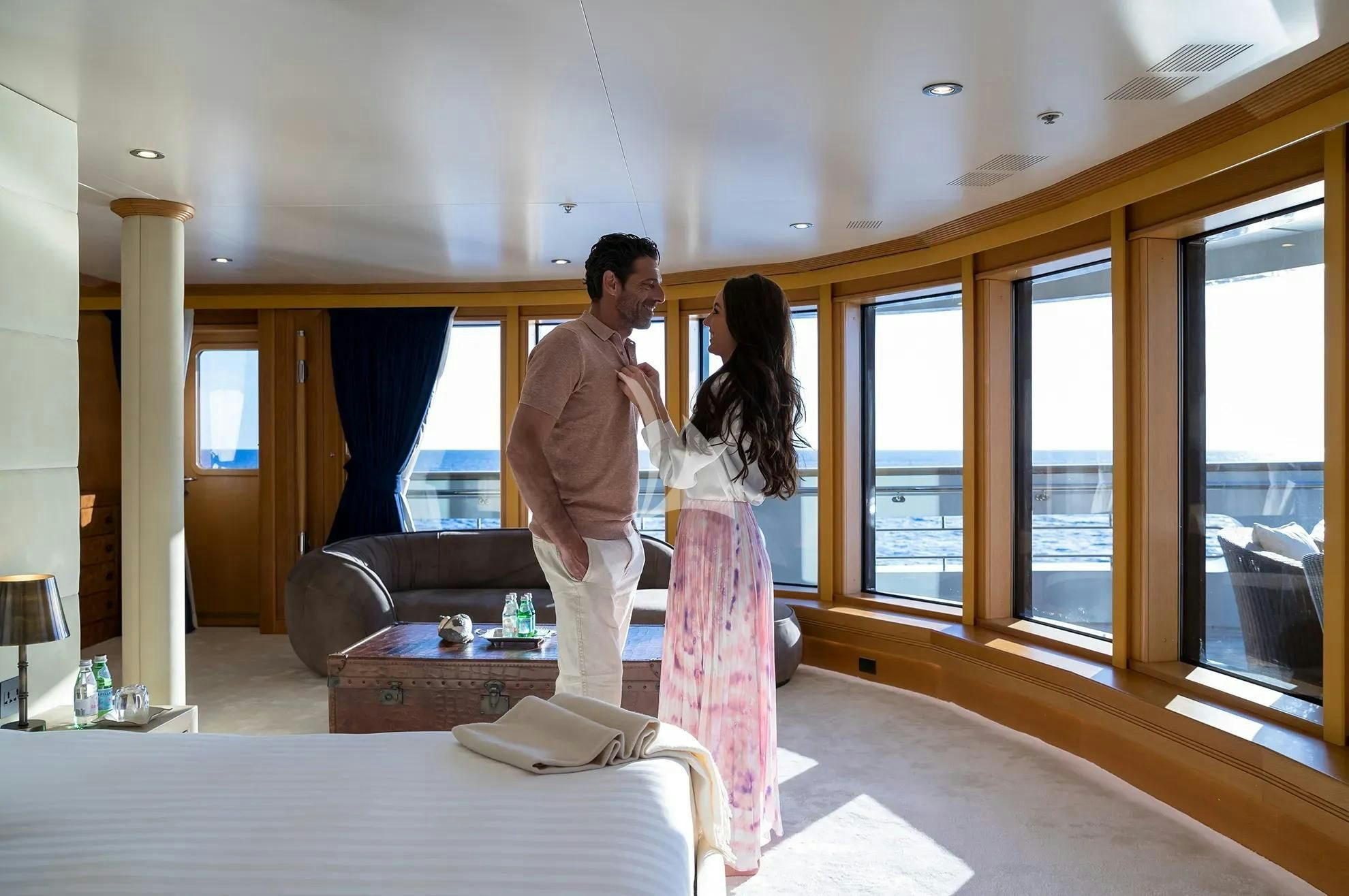 a man and woman standing in a room with a table and chairs aboard BOADICEA Yacht for Sale