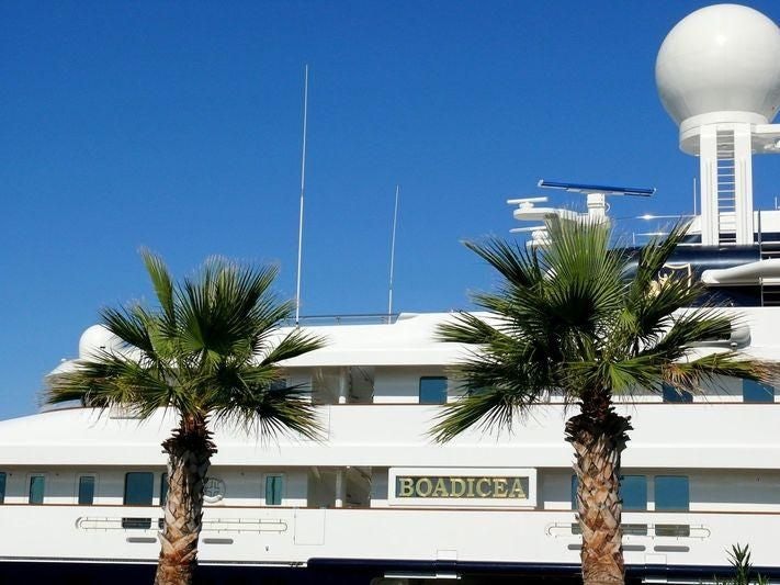a building with palm trees and a white building with a blue sky aboard BOADICEA Yacht for Sale