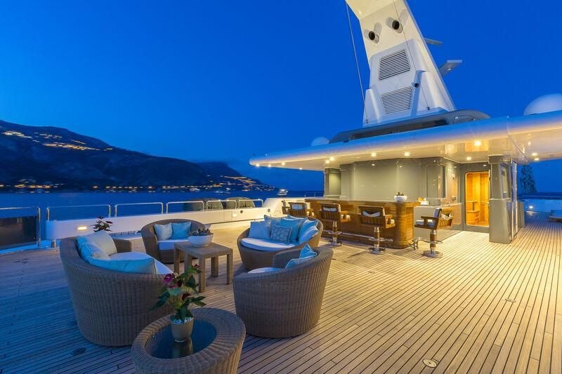 a patio with chairs and tables on it by a body of water aboard BOADICEA Yacht for Sale