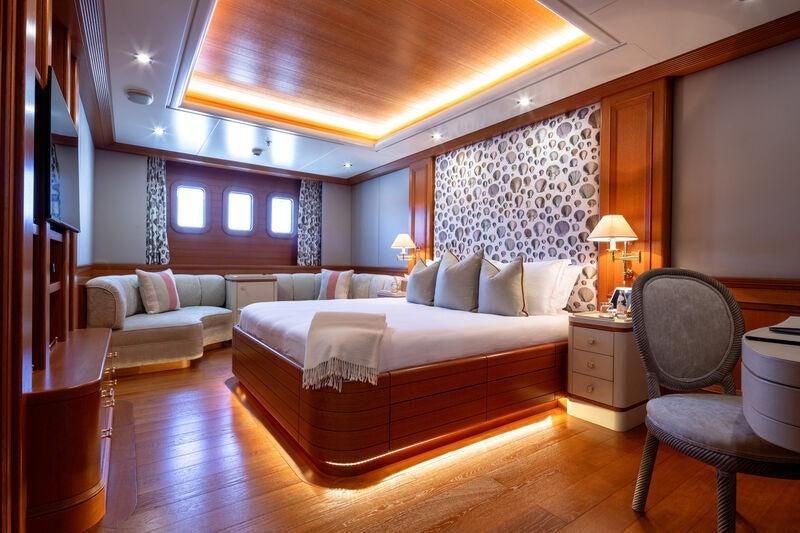 a large bedroom with a bed and a chair aboard BOADICEA Yacht for Sale