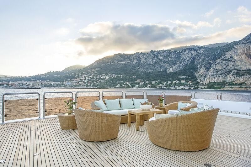 a table and chairs on a deck overlooking a body of water aboard BOADICEA Yacht for Sale