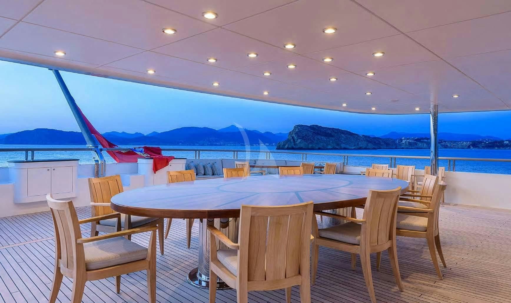 a table and chairs in a room with a view of the mountains aboard BOADICEA Yacht for Sale