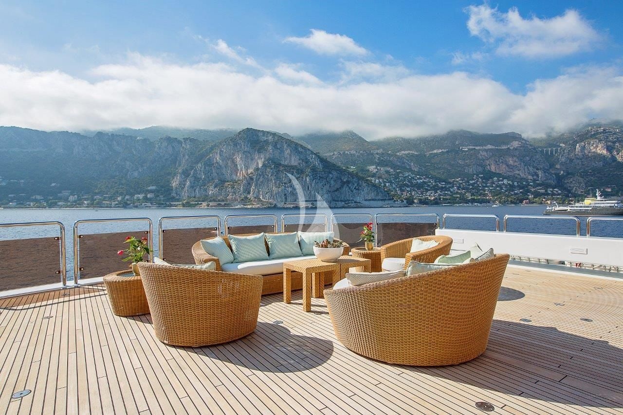 a table and chairs on a deck overlooking a body of water aboard BOADICEA Yacht for Sale