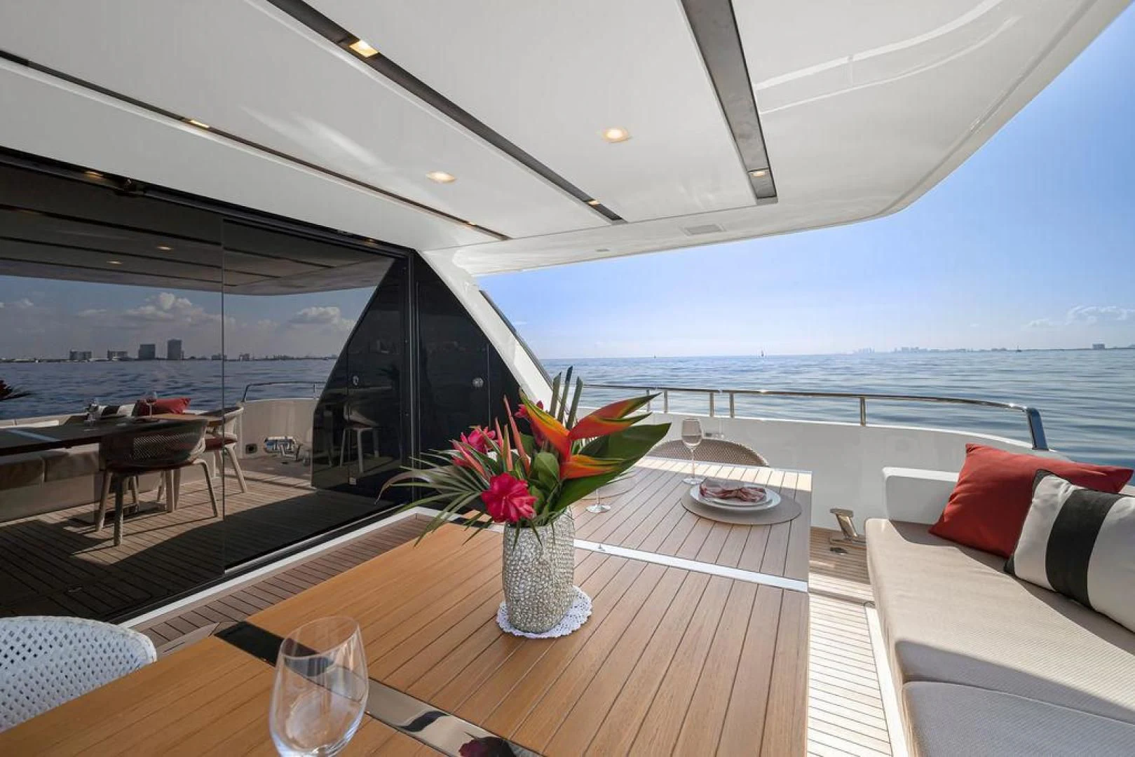 a glass vase with flowers on a table in a room with a view of the ocean aboard JUJU Yacht for Sale