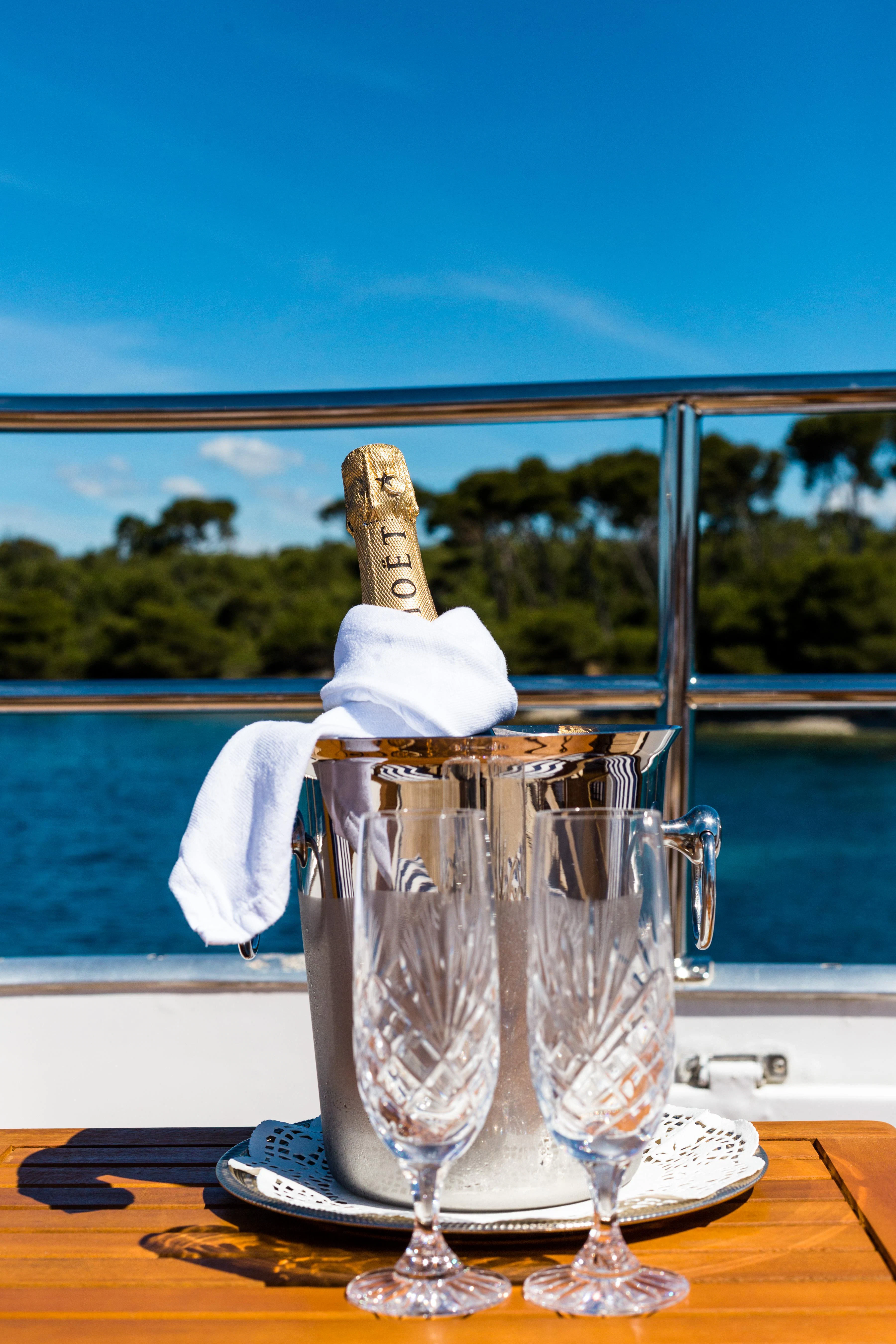 a glass with ice and a napkin on a table with water and trees in the background aboard STAR OF THE SEA Yacht for Sale