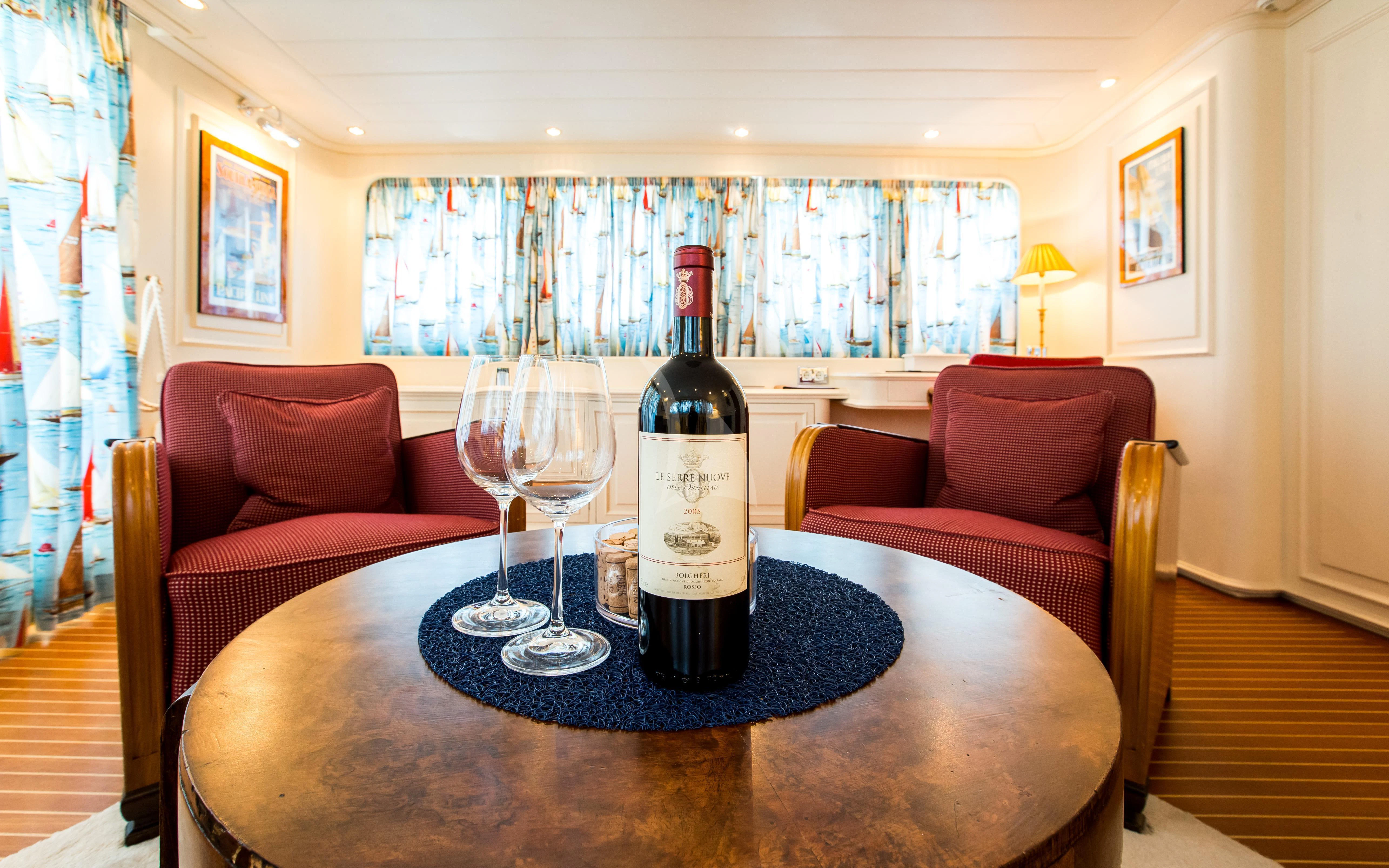 a wine bottle and a glass on a table in a living room aboard STAR OF THE SEA Yacht for Sale