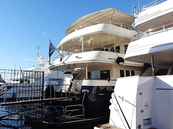 a large white boat with a flag on the front aboard LIBERTA Yacht for Sale