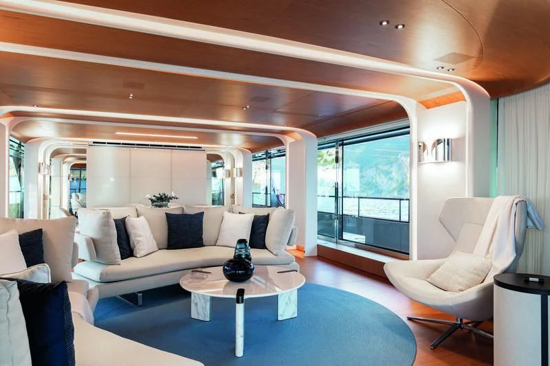 a living room with a large blue rug and white furniture aboard LEGEND Yacht for Sale
