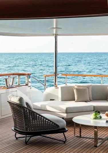 a white couch and a table on a deck overlooking the ocean aboard LEGEND Yacht for Sale
