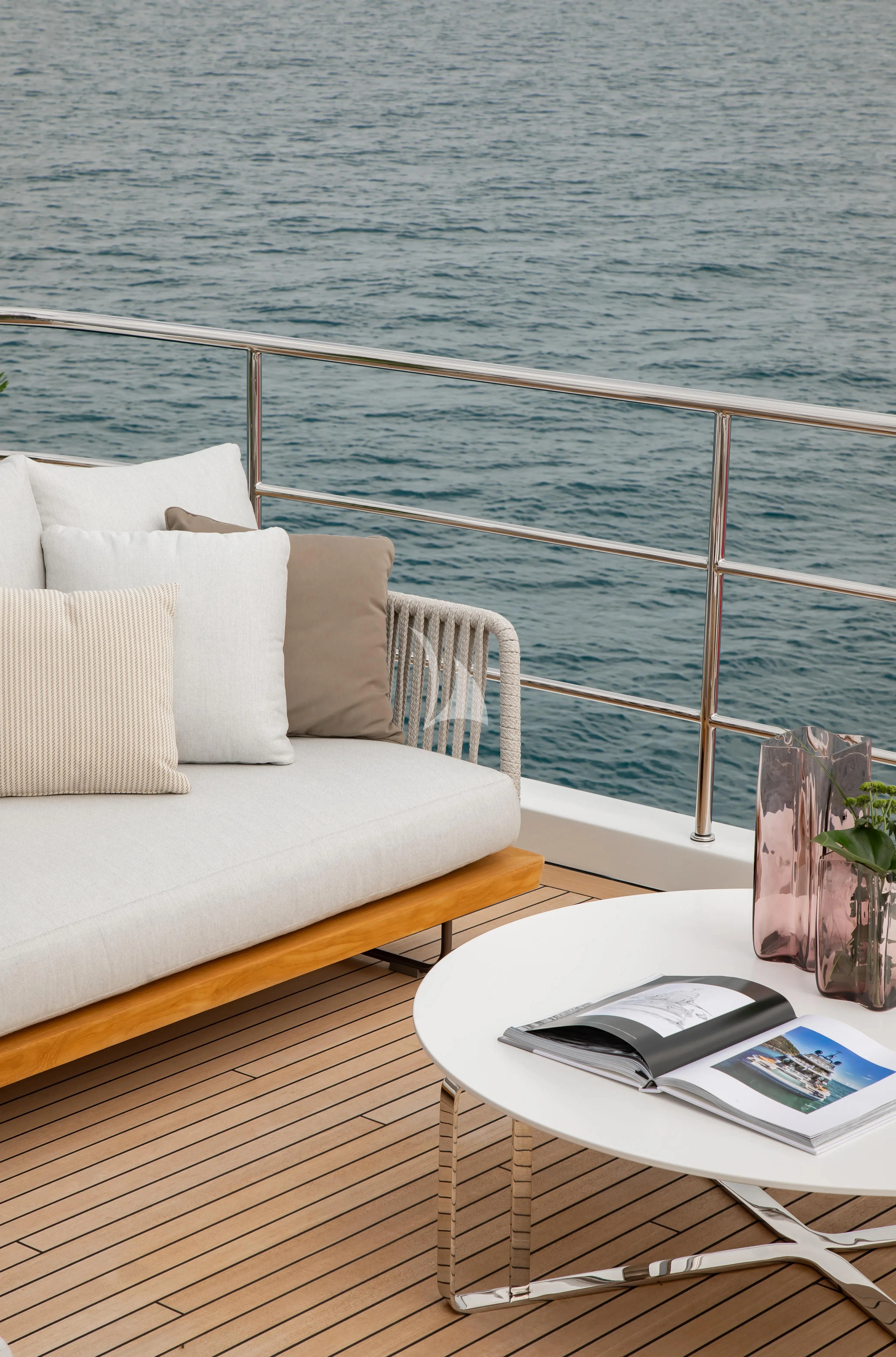a white couch and a table on a balcony overlooking a body of water aboard LEGEND Yacht for Sale