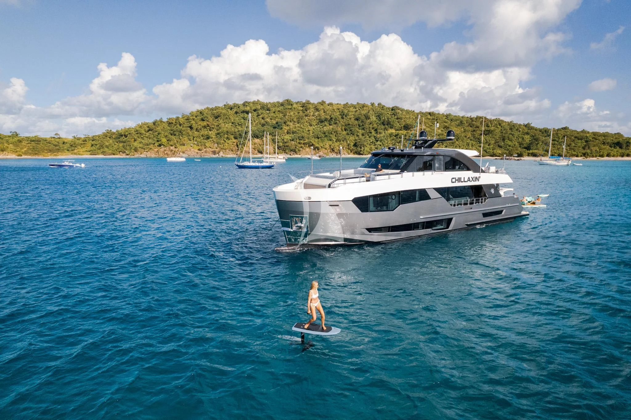 a person on a surfboard in the water next to a boat aboard CHILLAXIN' Yacht for Sale