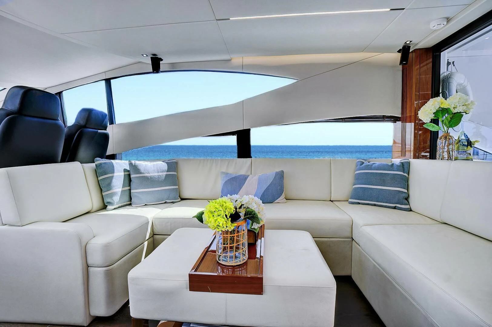 a white living room with a large blue and white sofa and a table with a vase of flowers aboard ONCE AROUND Yacht for Sale